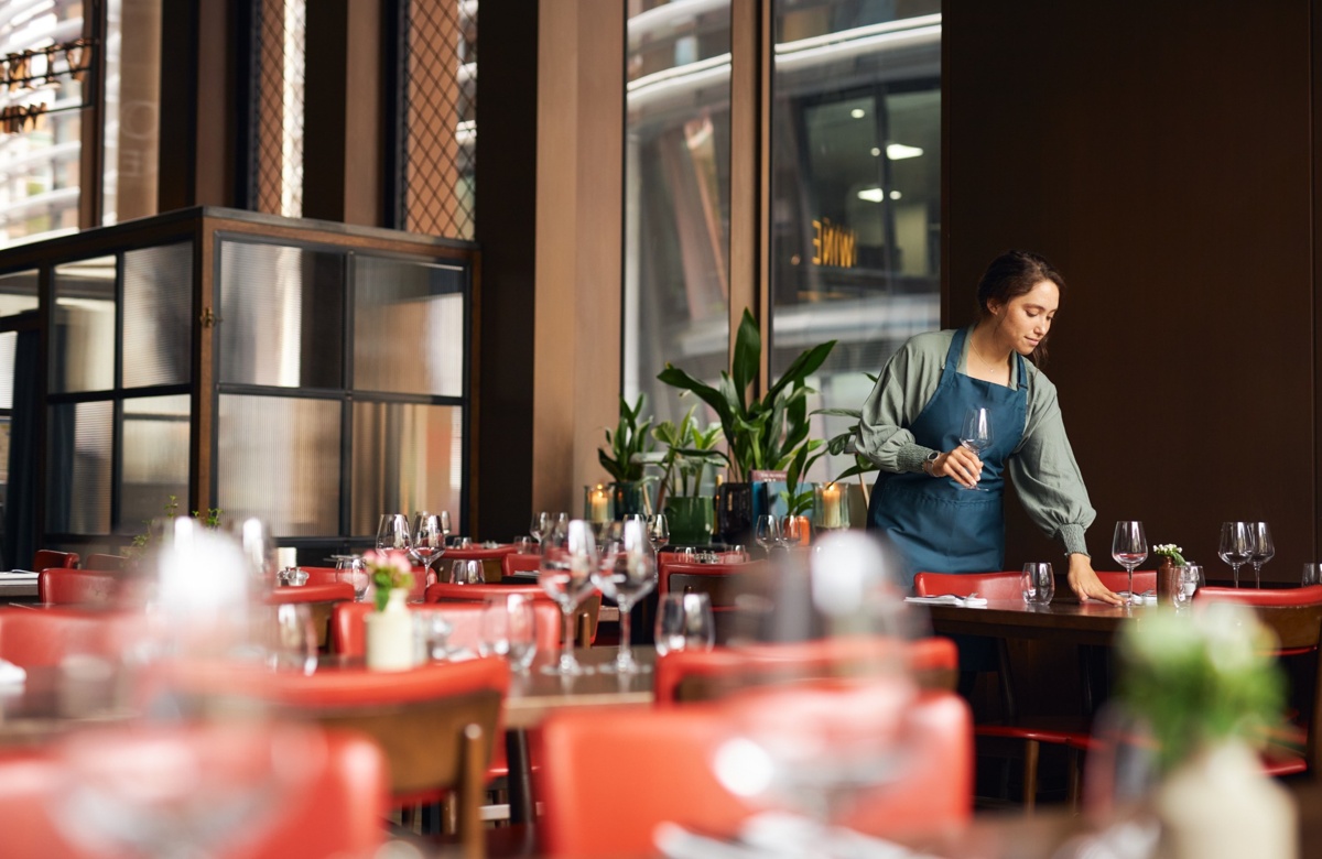A woman setting tables in a restaurant